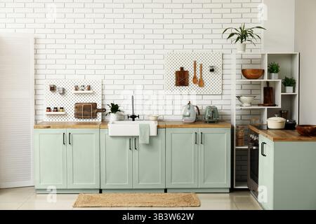 Stylish light kitchen with green furniture Stock Photo