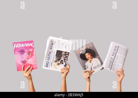 Female hands with different magazines and newspapers on grey background Stock Photo