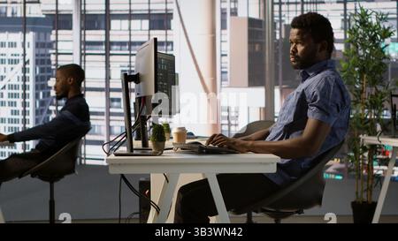 African american man designing, developing and maintaining software applications using various programming languages. System administrator debugging company servers, preventing failures, camera A Stock Photo