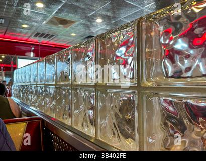 Glass block dividing wall next to tables in a diner or  restaurant with tin ceiling. Stock Photo
