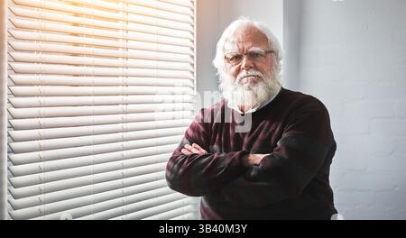Senior man standing with arms crossed, looking angry and unhappy at home. Portrait of the face of a mature, retired and expert professor with arms Stock Photo