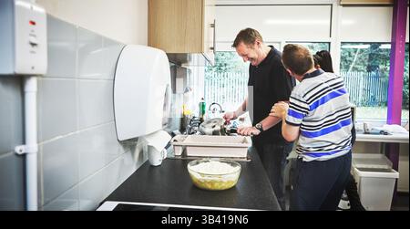 Volunteer, charity and community with a man working in the kitchen of a learning and development center. Healthcare, wellness and activism with a male Stock Photo