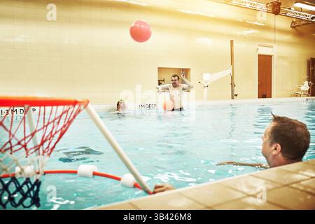 Pool, down syndrome and man with learning disability playing water basketball for a fitness workout. Inclusion, sports and disabled person swimming to Stock Photo