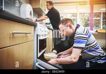 Food, development and disability by man learning basic baking skills in healthcare facility for people with special needs. Mature couple helping male Stock Photo