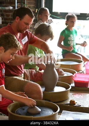 July 20, 2015 - St. Petersburg, Florida, U.S. - SCOTT KEELER   |   TIMES.Instructor Matt Schiemann, St. Petersburg, center, shapes a pitcher on the potters wheel as students work on their own projects on the potters wheel 7/20/15, during a session of the Morean Center For Clay's Summer Clay Camp in St. Petersburg. 45 students, ages 5-15 are participating. The camp runs each day from 9am to 3pm. Students learn various aspects of pottery making including learning to use the potters wheel. Their work will be Raku fired on Friday at the center according to Schiemann. Openings are still available f Stock Photo