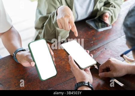 Hands of male and female friends using mobile phones on table in coffee shop. Blogger pointing finger on phone screen, showing new post. Sharing the s Stock Photo