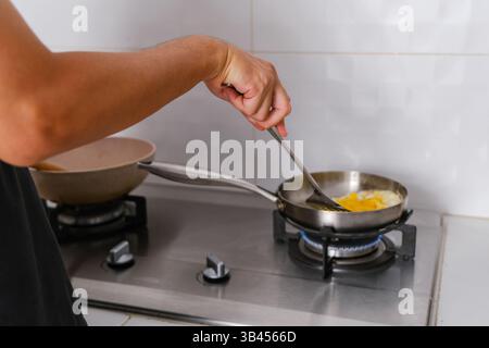 Man cooking fried egg in a frying pan on the stove. Stock Photo