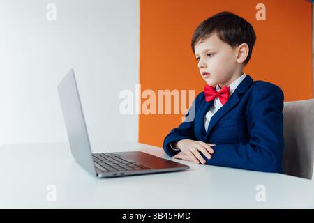Boy in school uniform working on laptop online Stock Photo