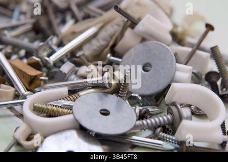 Close-up view of assorted screws, nuts, and washers on a work surface, displaying various materials and sizes. Stock Photo