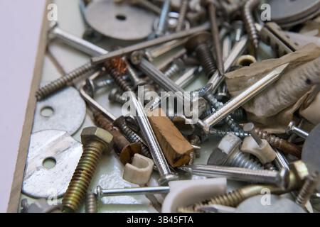 A collection of screws, nuts, and bolts scattered on a workbench ready for use in various projects. Stock Photo
