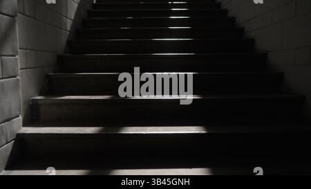 Light beams cutting through darkness on a staircase, enhancing the dramatic and mysterious atmosphere with striking contrasts and shadows Stock Photo