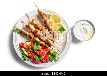 Grilled chicken kebab with fresh vegetable salad isolated on white background, top view. Mediterranean keto lunch with roasted souvlaki meat skewers, Stock Photo
