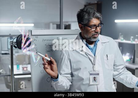 Scientist analyzing holographic data in high-tech laboratory surrounded by advanced equipment and detailed whiteboard notes. Conducting focused research in modern scientific environment Stock Photo