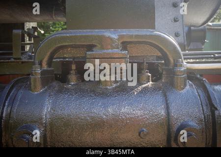 The black metal object has a black handle and is covered in black paint. The handle is attached to a machine, and the machine is likely used for indus Stock Photo