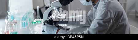 Researcher conducting scientific experiment in a well-equipped laboratory, wearing lab coat and gloves, working with various laboratory equipment Stock Photo