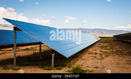 Closer perspective of a solar energy facility showing reflective photovoltaic panels aligned in a semi-arid area with clear skies Stock Photo