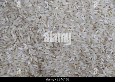 Close-up image showing a heap of uncooked white rice grains. Detailed view of grain texture and shape. Stock Photo