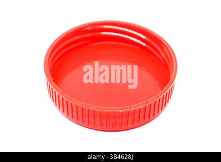 Overhead shot features a vibrant red plastic bottle cap with distinct ribbed texture, set against a stark white backdrop, highlighting its details. Stock Photo