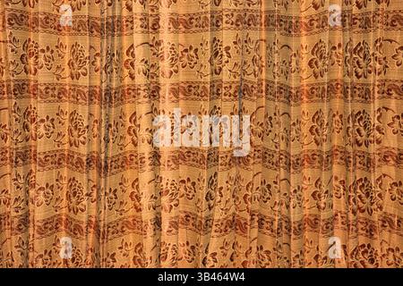 Close up showcasing a beige fabric with detailed brown flower pattern. The textile features a floral design with flower and scrolling foliage elements Stock Photo