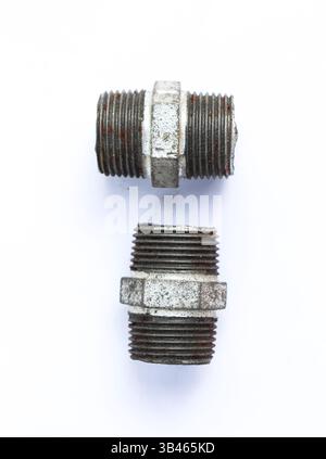 Close-up shows two galvanized iron pipe fittings with rusty threading, one slightly damaged, against a clean, stark white backdrop. Stock Photo