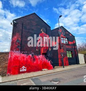Mo Salah mural by artist John Culshaw on Anfield Road, Liverpool, beneath a blue sky and white clouds. Stock Photo
