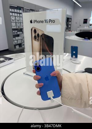 Female hand holding blue iPhone 16 in store. Apple authorized shop. The modern shop with apple products: Iphone, Macbook, Ipad, Apple logo. Kazakhstan Stock Photo
