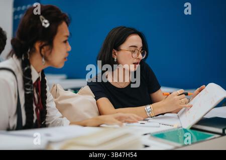 Students collaborating on class tasks with assistance from professor Stock Photo