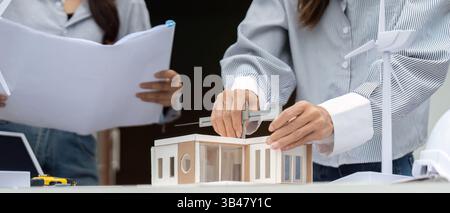 Sustainable Design and Collaboration. Architects discussing eco-friendly building models and renewable energy solutions. Stock Photo