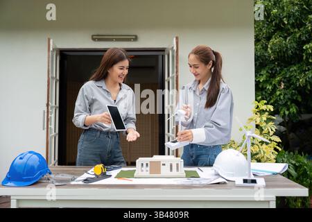 Sustainable Design and Renewable Energy. Two women architects collaborating on a green building project with a model. Stock Photo