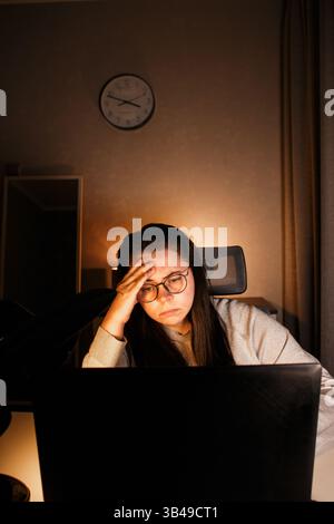 Young freelance accountant working remotely on laptop at home. Managing finances of business. Calculating incomes and expenses. Focusing on process Stock Photo