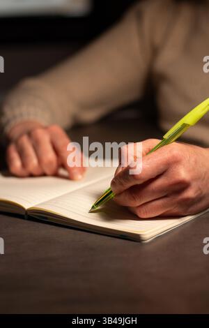 Left handed person making notes on blank page on notebook during psychological session, work conference, business meeting Stock Photo
