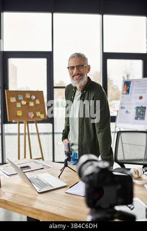 A man stands confidently in a bright office, engaging in a collaborative brainstorming activity. Stock Photo