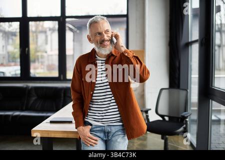 A happy man chats on his phone in a bright, stylish office with modern decor. Stock Photo