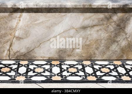 Close-up image showcasing a decorative marble wall and a detailed black and white tiled floor with geometric patterns, presenting a blend of textures Stock Photo