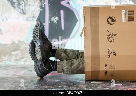 feet of homeless man  vagrant sleeping on the street  poking out of the end of a cardboard box in santa cruz de tenerife canary islands spain Stock Photo