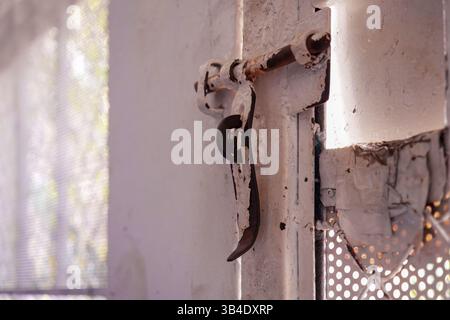 Rusty metal latch on an old white door Stock Photo
