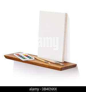 Blank canvas, brushes and paints on oak wooden shelf isolated on white background, angle view, template for designer Stock Photo