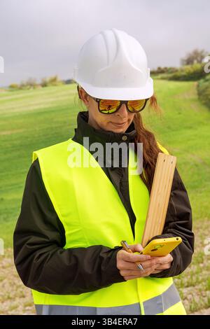 Female engineer using smartphone on construction site for renewable energy project Stock Photo