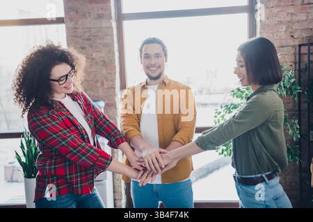 Group of young coworkers smiling while collaborating on a team-building activity in a bright modern office space Stock Photo