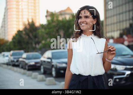 Facial recognition system identifying smiling woman on city street Stock Photo