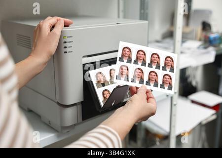 Worker with passport photos of women near modern printer indoors, closeup Stock Photo