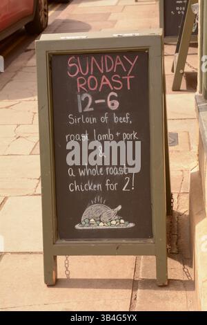 Chalkboard sign outside pub saying 'Sunday Roast 12-6 Sirloin of beef, roast lamb and pork and whole roast chicken for 2' Stock Photo