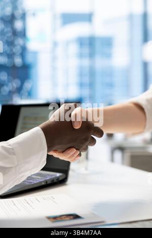 HR employee doing welcoming handshake with woman, reaching agreement after ensuing qualifications align with company expectations. Close up of recruiter in office greeting applicant, shaking hands Stock Photo