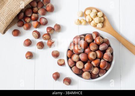 Hazelnut, whole and peeled hazelnuts in bowl and wooden spoon on white bright table, healthy food Stock Photo