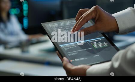 Data center admin responsible for installation of networking systems solving tasks in workspace. Close up of tablet used by IT worker doing maintenance on server farm gear, camera A Stock Photo
