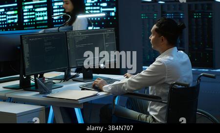 Person with disability in inclusive high tech server room facility ensuring data remains shielded from threats. Wheelchair user protecting data center hardware equipment, camera A Stock Photo