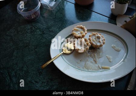 leftover tartlets on a white plate with a golden fork, Denmark, April 24, 2025 Stock Photo