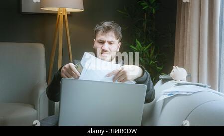 Frustrated young man struggling with bills and paperwork while working from home Stock Photo