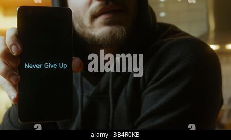 Man Holding Smartphone Displaying Never Give Up Message Motivation and Inner Strength Concept Stock Photo
