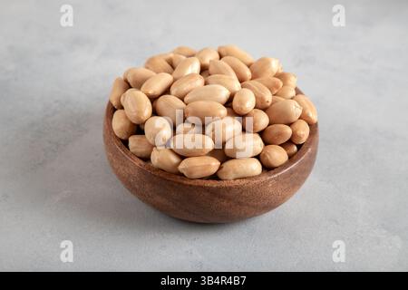 Bowl full of roasted peeled peanuts on light blue background,closeup Stock Photo